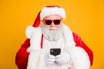 Close up photo of funny cool overweight santa claus in red hat headwear using smartphone search winter season tradition sales end x-mas 2020 greetings isolated over bright color background