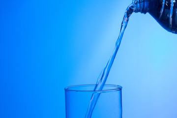 Agua entrando en un recipiente transparente de crital o plástico; agua salpicando 