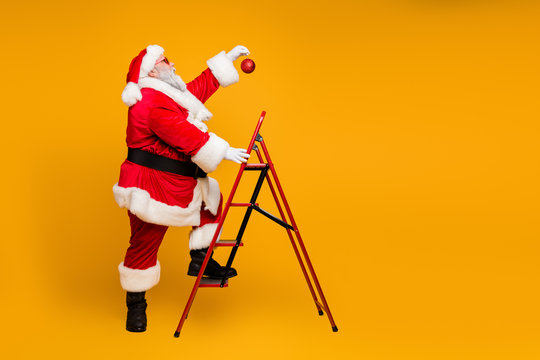 Full body profile side photo of funky funny white beard christmas father climb ladder want hang x-mas decorative tinsels make steps isolated over yellow color background