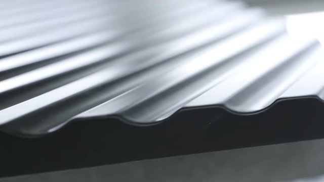 Close up side of black wavy roof tiles on blurred background. Action. Black wavy roofing material, constructional materials.