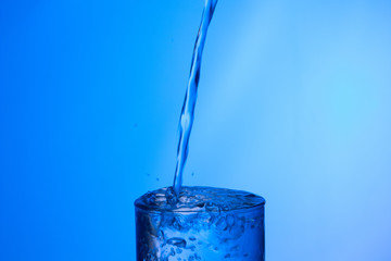 Agua entrando en un recipiente transparente de crital o plástico; agua salpicando 