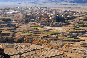 Obraz premium Terrace fields and ruins of medieval adobe mud-brick Kharanaq town. Iran.