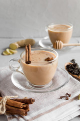 A traditional Indian drink made of milk, black tea and spices. Masala tea with cinnamon and anise on a grey concrete background. Copy space, side view, close-up.