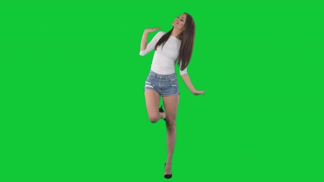 Happy young woman dancing joyfully relaxed and smiling.  Full body isolated on green screen chroma key background	