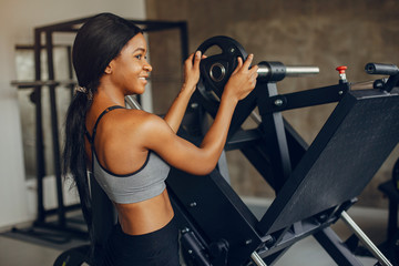 Fototapeta na wymiar Beautiful black girl in the gym. A woman in a gray top