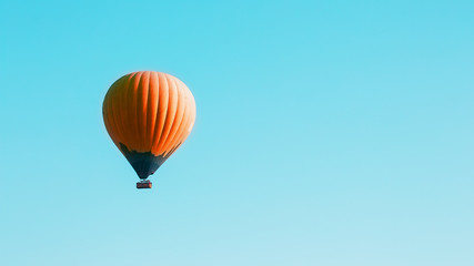 Fototapeta premium Orange balloon soars against the blue sky