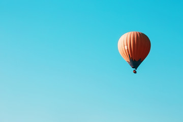 Orange balloon soars against the blue sky