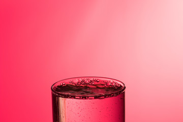 Chorro de agua entrando en un vaso lleno de agua produciendo un chapoteo y burbujas, cayendo gotas...
