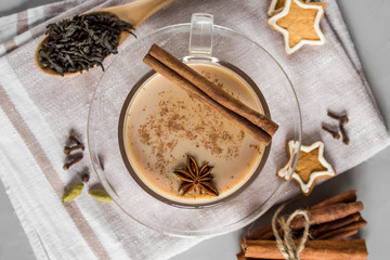 Masala tea with spices on a gray concrete background. Traditional Indian hot drink made of black tea, milk and spices. Top view, copy space.