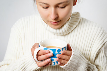 young woman girl in a warm sweater with a cup of hot coffee. on white