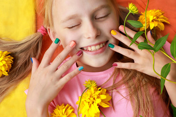 Bright and colorful children's manicure on the nails of girls with yellow flowers and good mood.