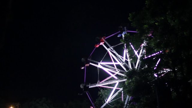A ferris wheel at night during the town carnival.