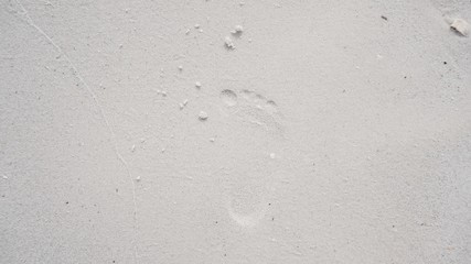 The right footprint of a child on a white sand beach.