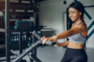 Fototapeta premium Beautiful black girl in the gym. A woman in a gray top