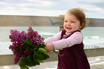 pretty little girl offering a bouquet of lilac to her mother