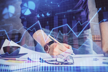 Double exposure of man writing on paper with forex graph.
