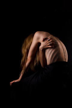 A girl with a bare back, severe thinness and protruding ribs. The concept of anorexia and bulimia, a disease of thin people. The struggle of the evil spirit in a girl, suffering and poverty.