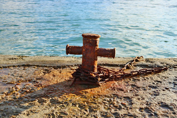 Naklejka premium Rusty bit with a chain on a stone pier