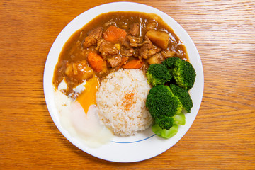 Pork Curry Rice on wooden background ( Onsen tamago, Potato, enoki mushroom, onion, broccoli, Japanese style,)