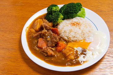 Pork Curry Rice on wooden background ( Onsen tamago, Potato, enoki mushroom, onion, broccoli, Japanese style,)