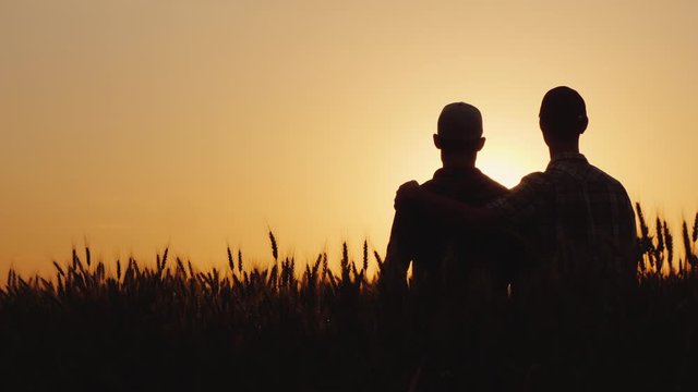 Two gay men stand hugging at sunset