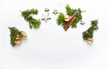 An arrangement of Chritsmas decorations, cinnamon sticks and evergreen twigs on white background....