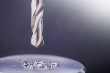 metal drill bit make holes in steel billet on industrial drilling machine with shavings. Metal work...