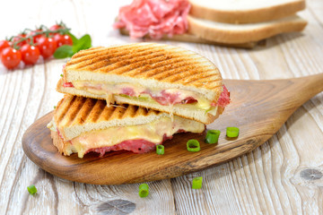 Getoastetes und im Kontaktgrill gepresstes italienisches Panini mit Serrano Salami, Käse , Tomaten...