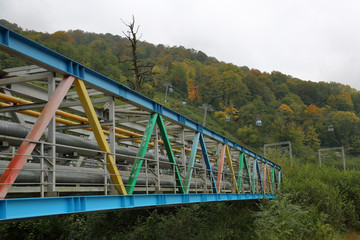 Industrial pipeline from multi-colored piles in a mountainous forest area