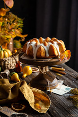 homemade tasty baked bundt pumpkin cake with glaze on top on wooden cake stand