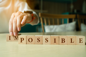 Business woman hand take out wooden cube with word impossible to possible, Personal...