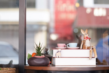 Wooden vintage rabbit. A wooden vintage rabbit toy is sitting on the old books with pastel teacups. Easter bunny decoration for the Easter egg hunting. Copy space on top for your text.