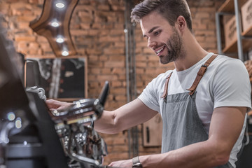 Side view shot of a male barista making a cup of coffee - obrazy, fototapety, plakaty