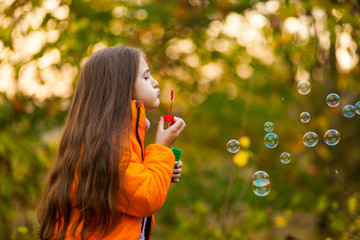 caucasian child girl blowing soap bubbles outdoor at sunse