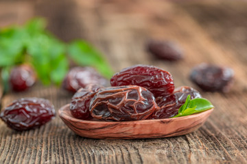 Juicy dates in a bowl on a old wooden table .