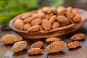 Almonds in wooden bowl on wooden table.