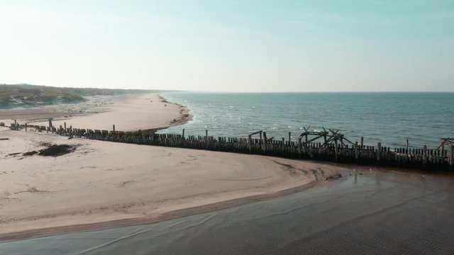 Old pier at sand beach, aerial view, waves, Baltic Sea, Lithuania. Beautiful sandy seaside, vacation location