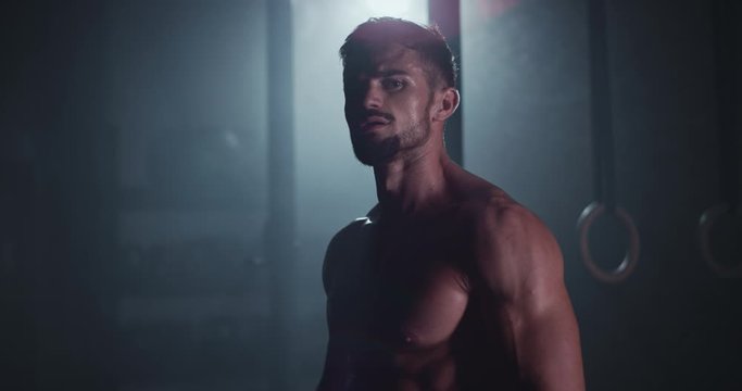 Brutal attractive athletic guy looking straight to the camera while doing his workout exercises he get sweating and tired