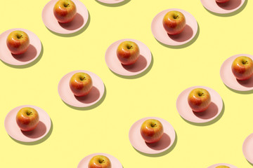 Fresh apples in plate on yellow background. Vibrant colorful pattern