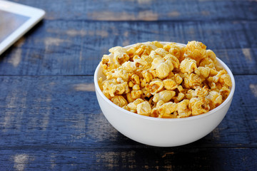snack caramel popcorn in white bowl on wood background