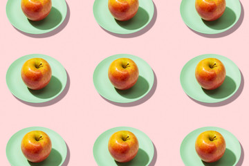 Fresh apple in plate on pink background. Vibrant colorful pattern
