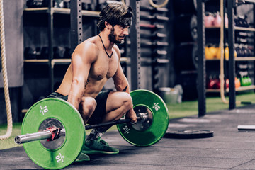 strong and athletic man doing barbell workout in modern gym