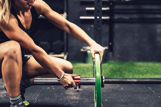 Side view of muscular woman preparing for training with heavy weight in gym