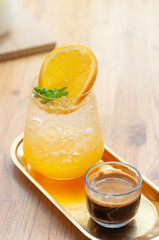 Orange soda sparkling espresso coffee shot, mixing coffee menu with orange slice on table, summer juice.