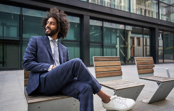 Glad ethnic entrepreneur smiling while sitting outside