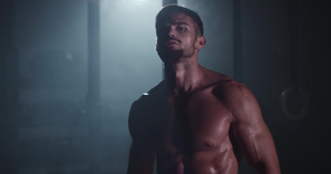 In front of the camera charismatic guy with a brutal face after his workout training have a break looking straight to the camera