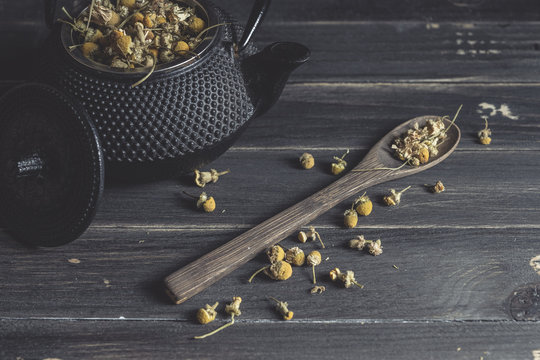 Dried daisy heap in wooden spoon on dark table for tea making