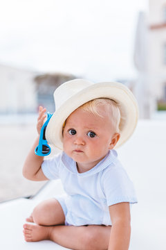 Frontal view of a blond baby with hat on the beach