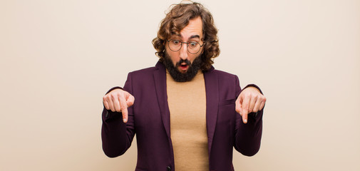 young bearded crazy man with open mouth pointing downwards with both hands, looking shocked, amazed...