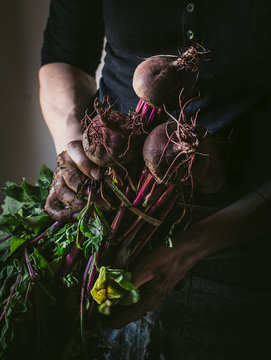 Faceless person with bunch of beetroots and key
